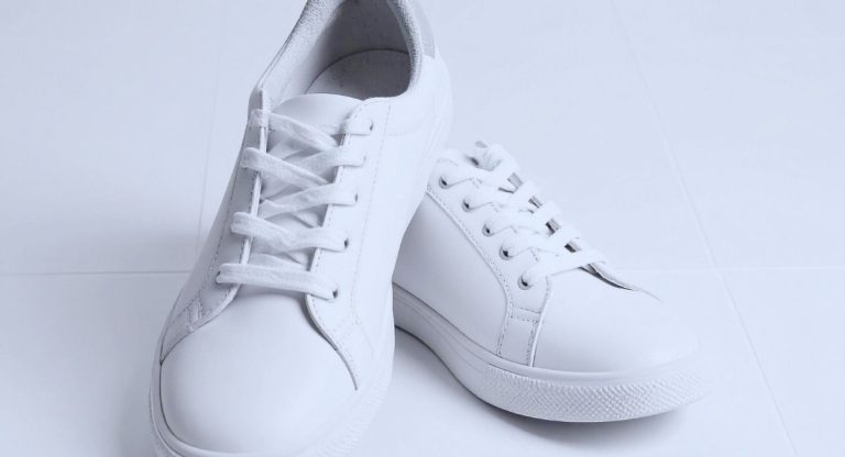 Paire de baskets blanches en cuir posee sur un sol clair