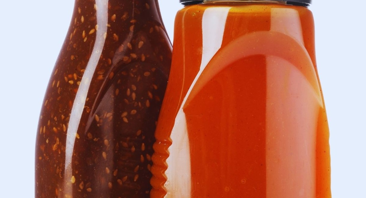 Deux bouteilles de sauce l une brune aux graines de sesame l autre orange