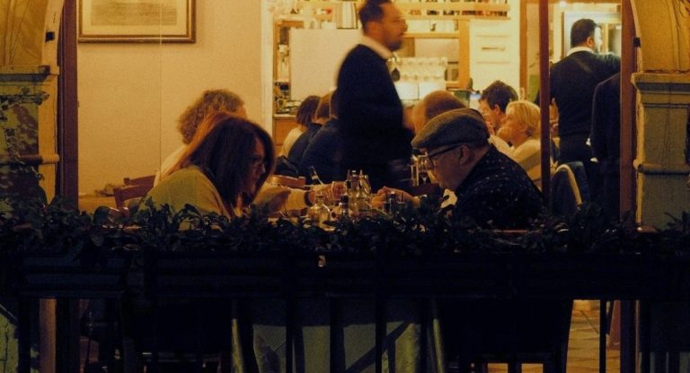 Clients attables en terrasse d un restaurant eclaire a la tombee de la nuit