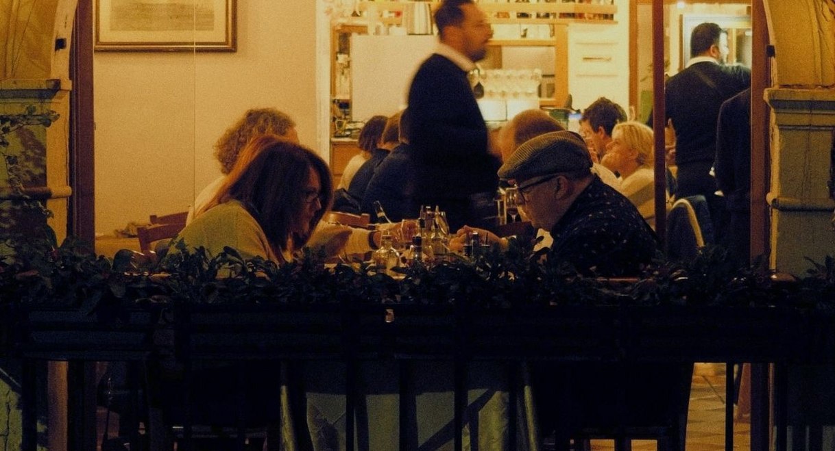 Clients attables en terrasse d un restaurant eclaire a la tombee de la nuit