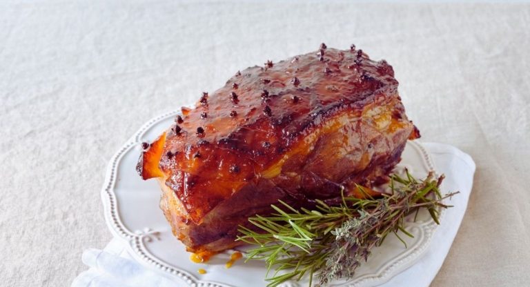 Gros jambon roti et glace pique de clous de girofle servi sur un plat blanc