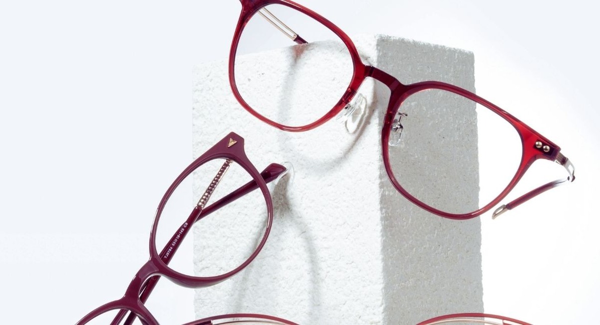 Montures de lunettes de vue rouges posees sur un bloc blanc de presentation