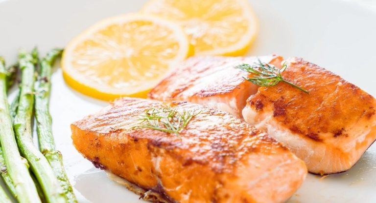 Deux paves de saumon grilles servis avec des asperges et des rondelles de citron