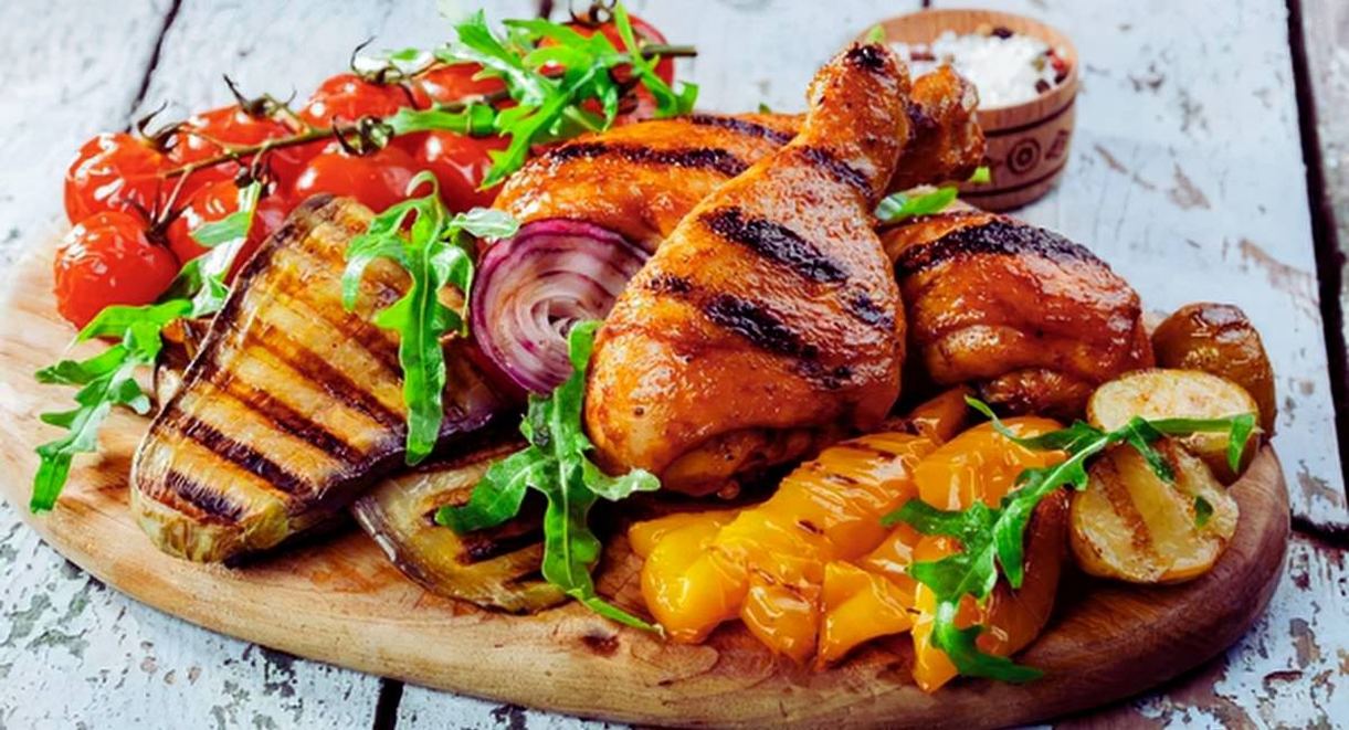 Planche en bois avec pilons de poulet grilles aubergine poivrons et tomates