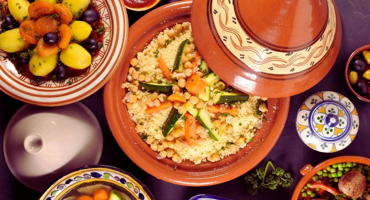 Table garnie de plats maghrebins avec un couscous aux legumes servi dans un tajine