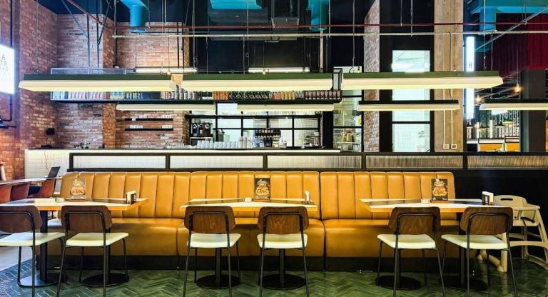 Salle de restaurant style industriel avec banquette en cuir ocre briques et neons