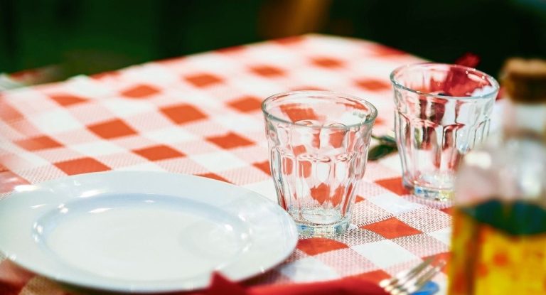 Table dressee avec assiette blanche verres et nappe a carreaux rouges et blancs