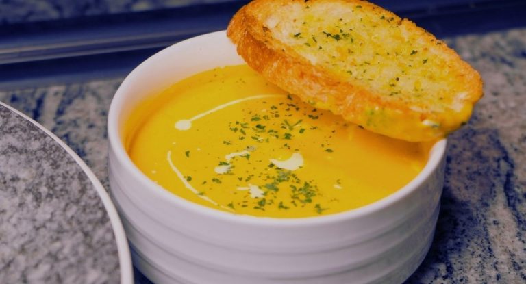 Bol de veloute de potiron avec un trait de creme et une tranche de pain grille