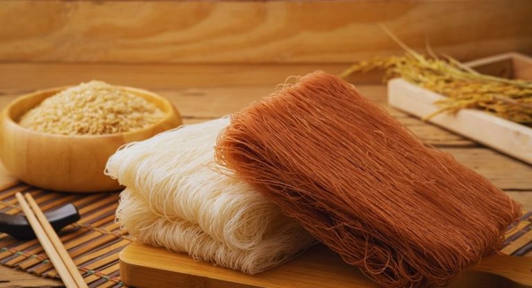Deux blocs de vermicelles de riz secs blancs et bruns sur une planche en bois